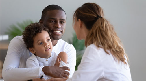 Father holding son speaking with health specialist