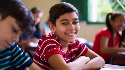 Young boy smiling sitting at desk in classroom