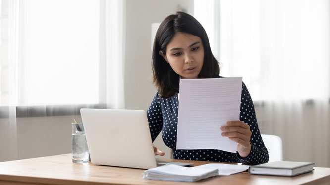 young women reading paper at a desk